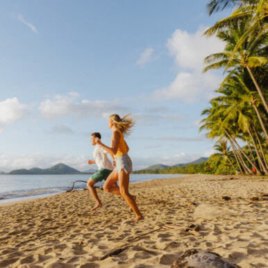Happy couple running down a North Queensland beach.