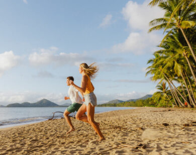 Happy couple running down a North Queensland beach.