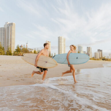 Photo of a young couple with surfboards on Surfers Paradise Beach.