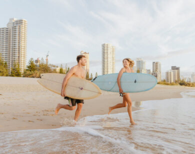 Photo of a young couple with surfboards on Surfers Paradise Beach.