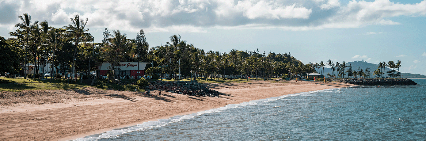 Sandy beach with palm trees and a beach club.