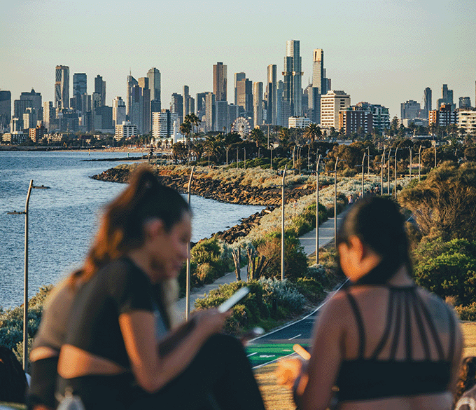 Two girls sit on a hill overlooking Brisbane.