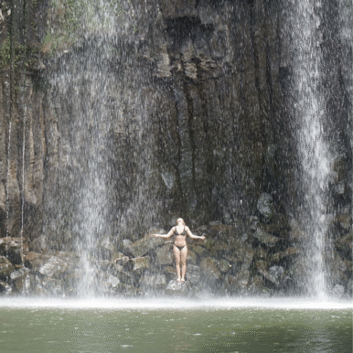 Woman standing on rocks in a waterfall.